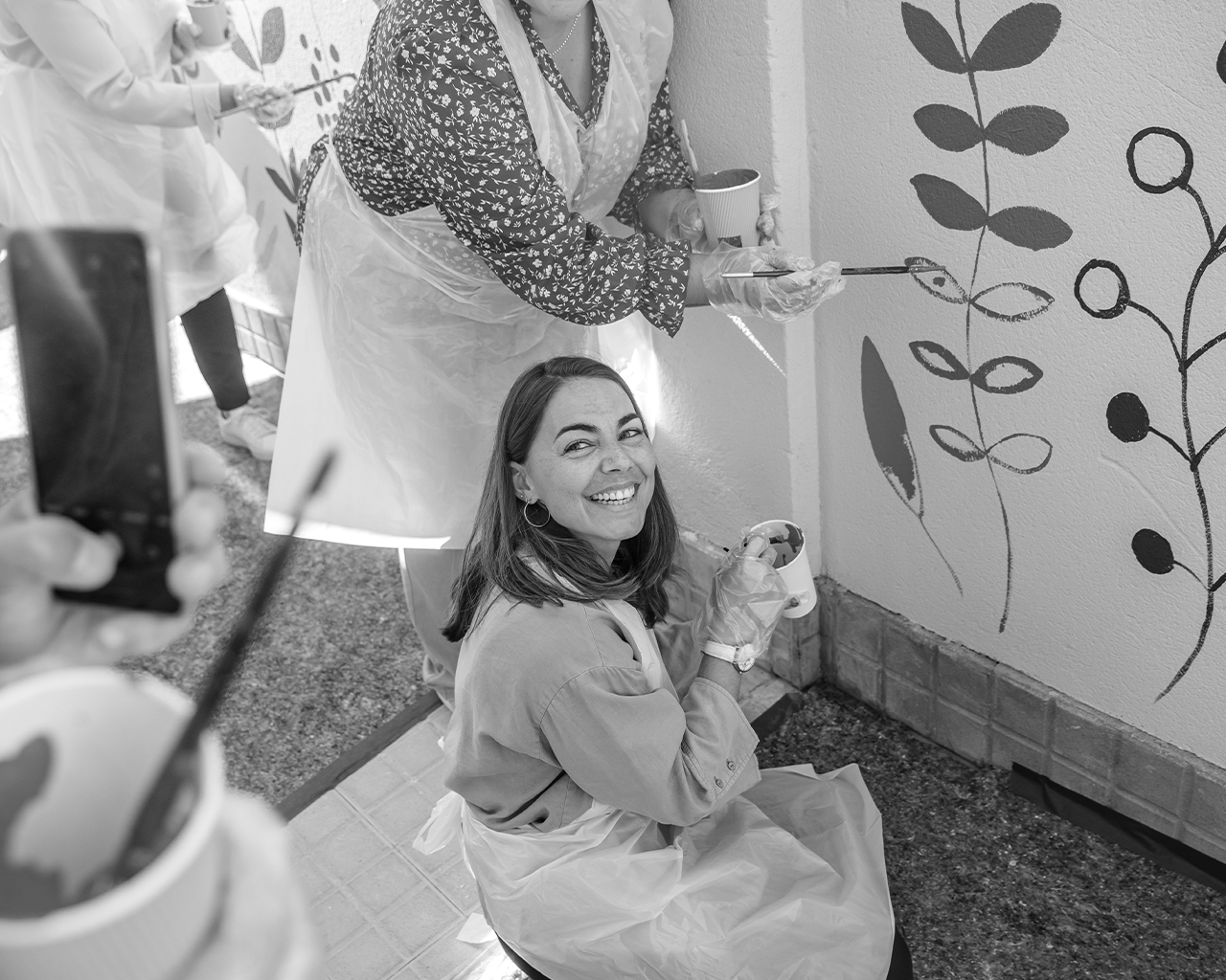 Equip de voluntaris de l'empresa Ferrer col·laborant en la creació d'un mural artístic i sostenible durant una jornada comunitària.