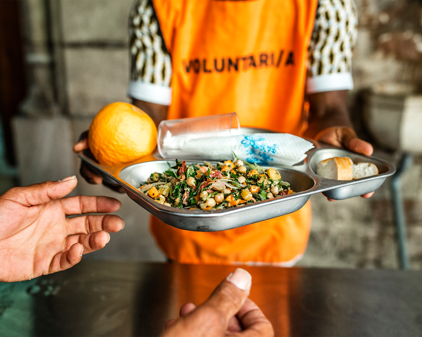 Voluntario de la fundación del grupo ferrer entregando una bandeja de comida