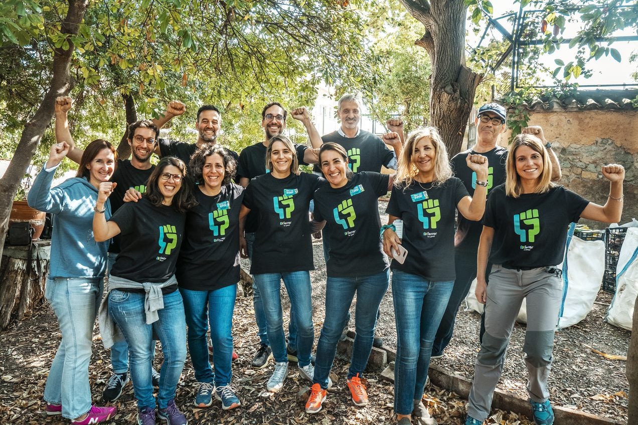 Group of people posing outdoors in Ferrer T-shirts, smiling and raising their fists in a natural environment.
