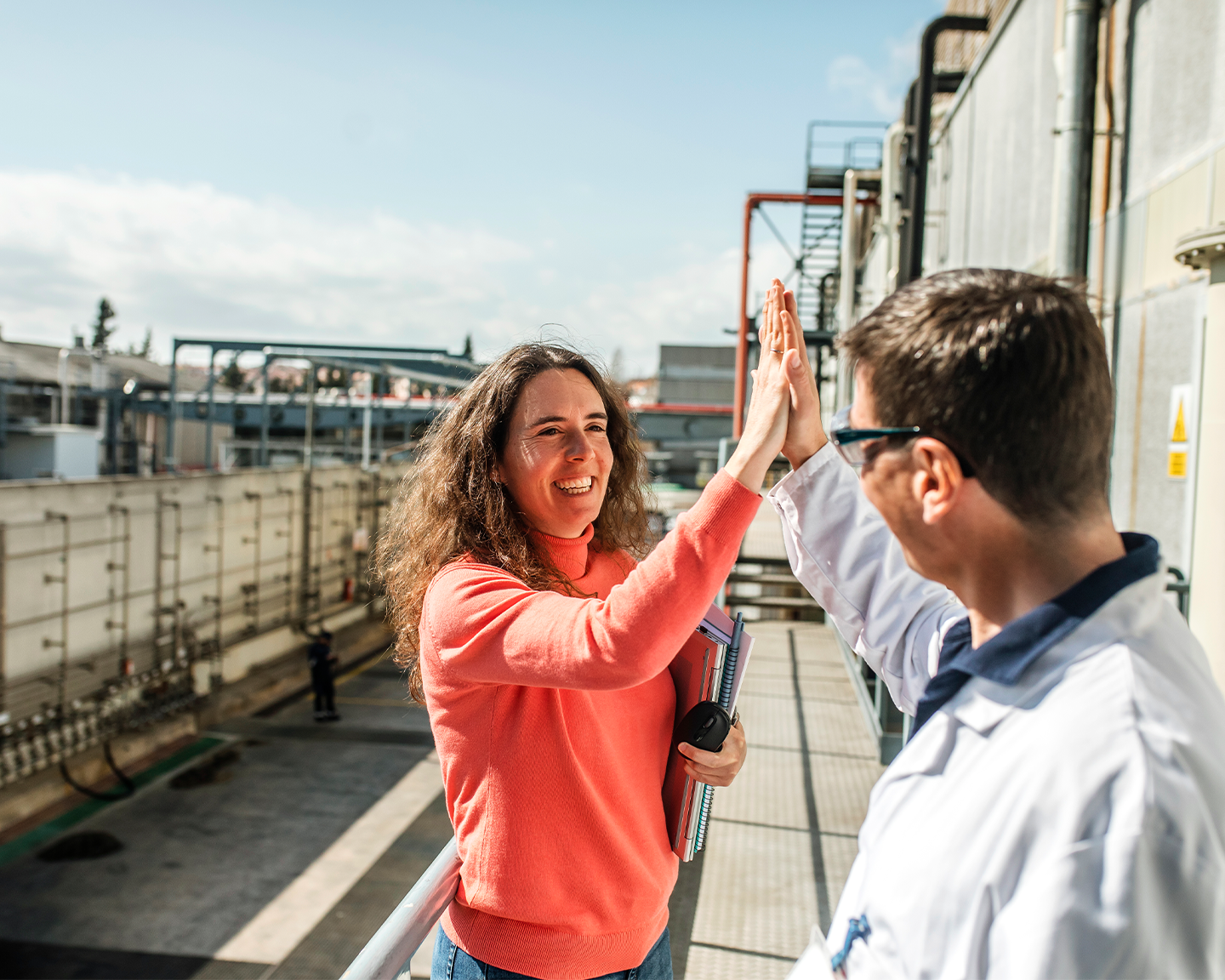 Two colleagues from Grupo Ferrer celebrating a work achievement in industrial facilities.
