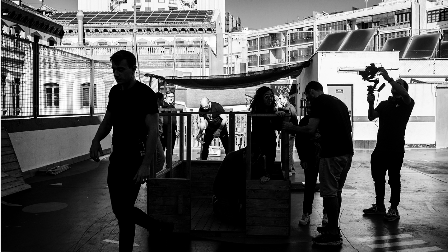 Voluntaris del grup Ferrer construint una estructura sostenible de fusta en un pati urbà durant una jornada d'acció social.