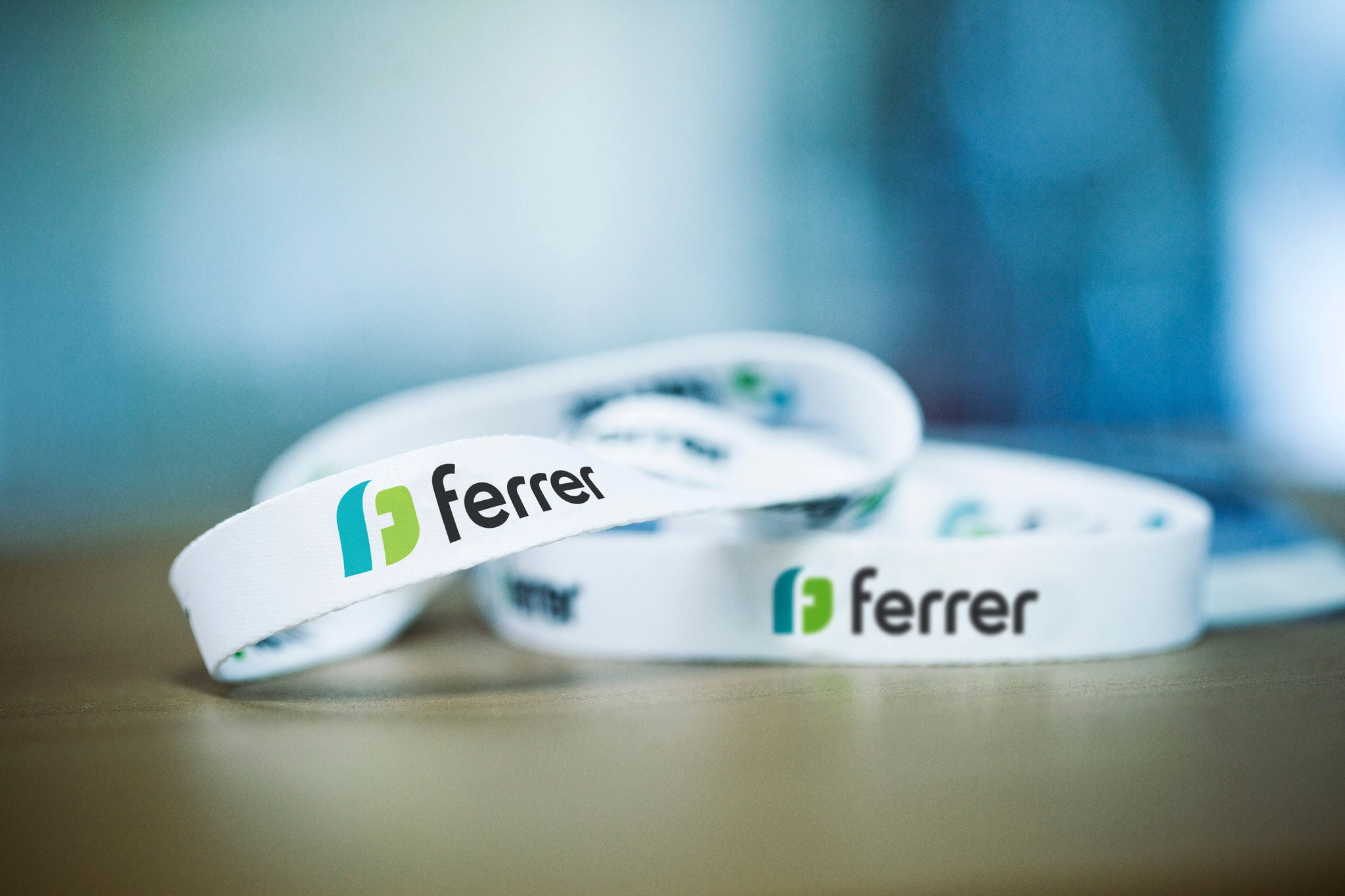 White Ferrer bracelets with the company's logo on a table, in a corporate environment.