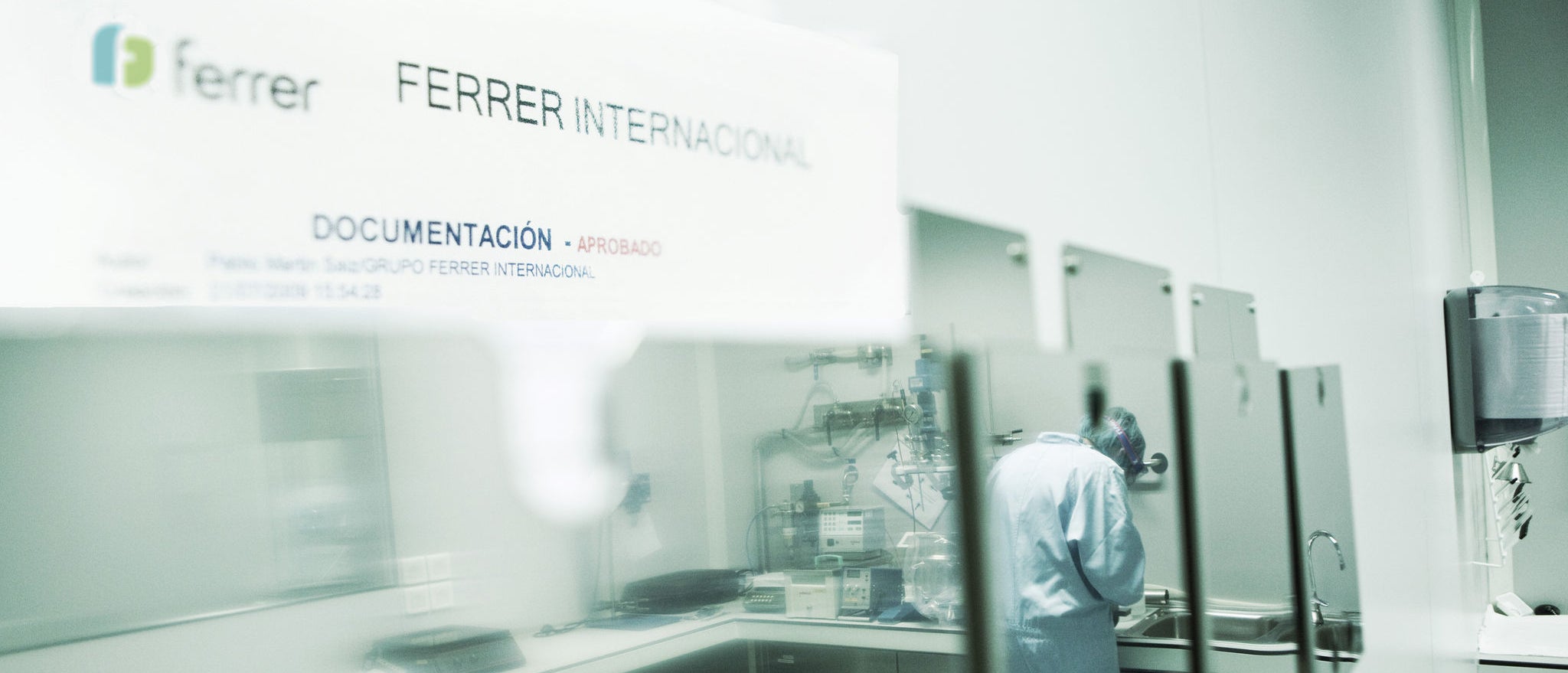 View of a documentation area at Ferrer Internacional facilities, with a person working in a technical or laboratory environment behind a glazed area.