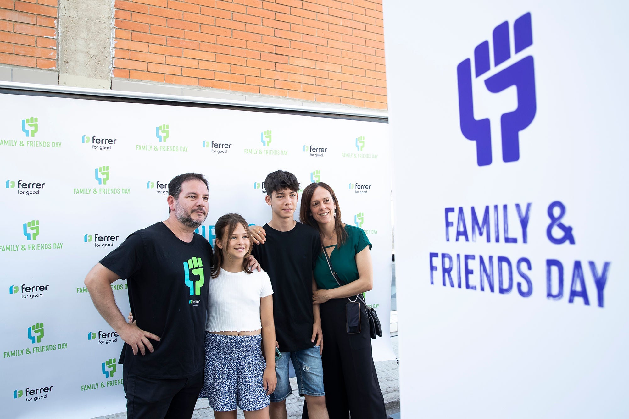  Una familia de cuatro personas posa sonriente frente a un panel publicitario durante la celebración del "Family & Friends Day" de la empresa Ferrer.