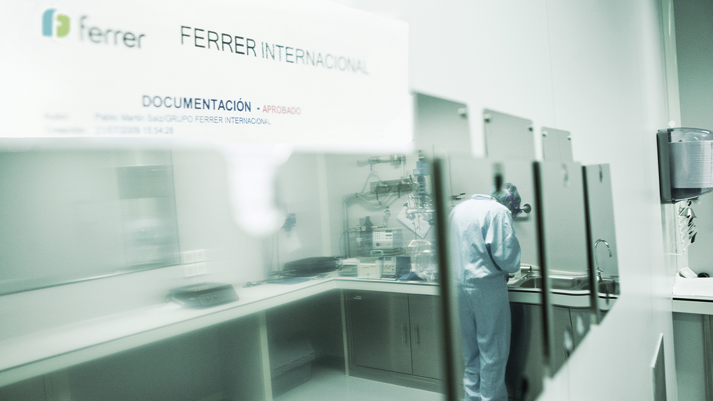 View of an R+D lab technician working in a Ferrer International lab through the reflection of a crystal.