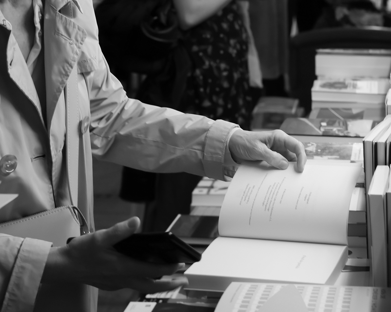 A person leafs through an open book at a literary counter during a cultural event of the Ferrer Foundation.