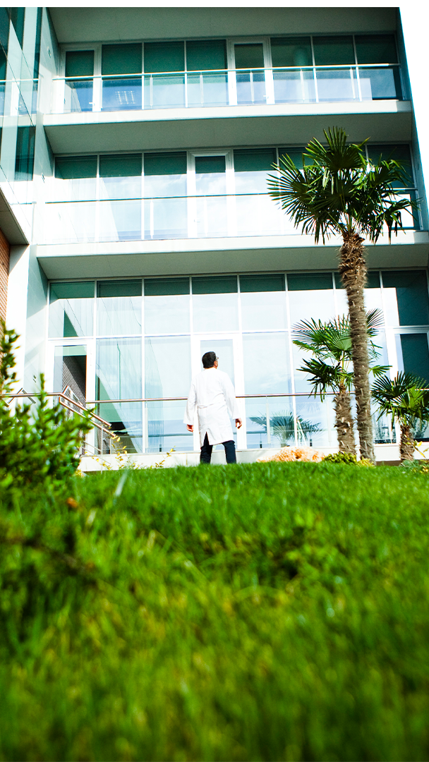 Ferrer professional walking in front of the company's corporate facilities, surrounded by green areas.