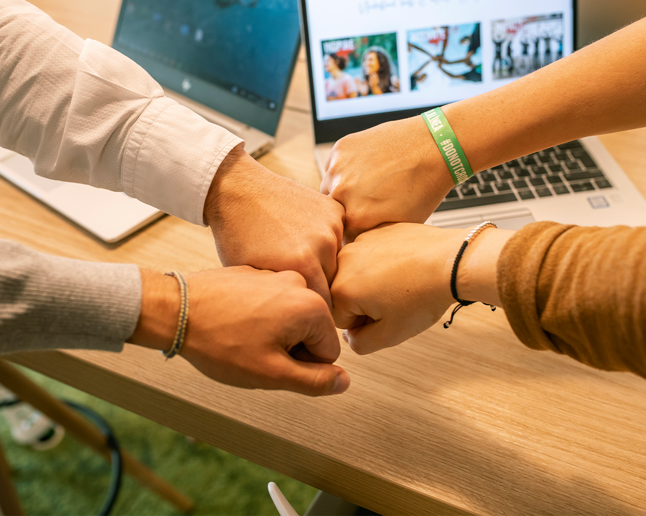 Members of the management committee of Grupo Ferrer fist bumping on the work table as a symbol of leadership, union and corporate governance.