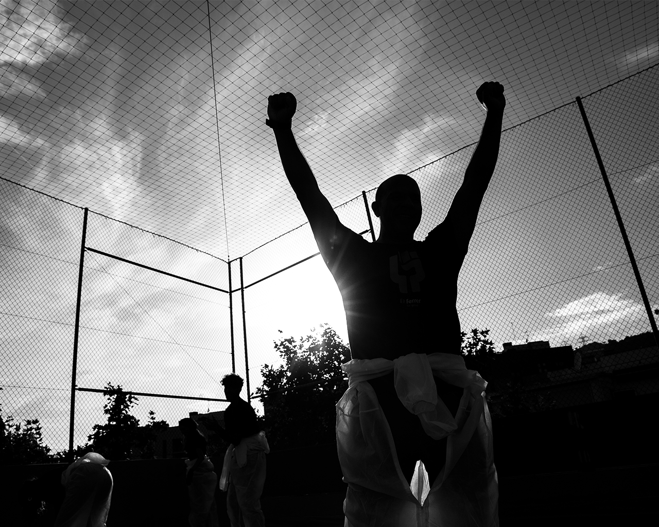 Silueta de un empleado de Grupo Ferrer celebrando con los brazos en alto al aire libre.