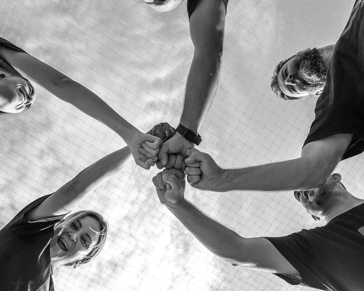 Voluntarios del grupo Ferrer con camisetas corporativas juntando los puños en señal de éxito y colaboración conjunta.