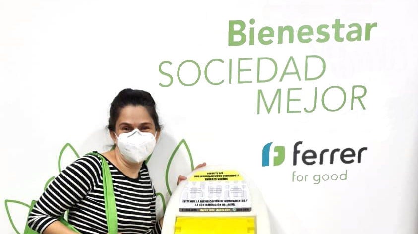 Mujer con mascarilla y camiseta de rayas junto a un panel de Ferrer que dice "Sociedad Mejor".