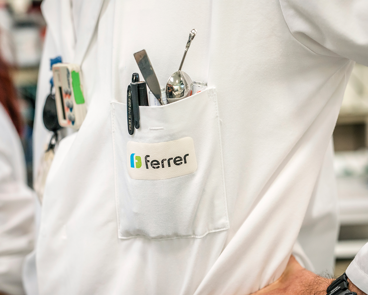Close-up of a scientist's uniform in Ferrer's R+D laboratory with the corporate logo on the coat.