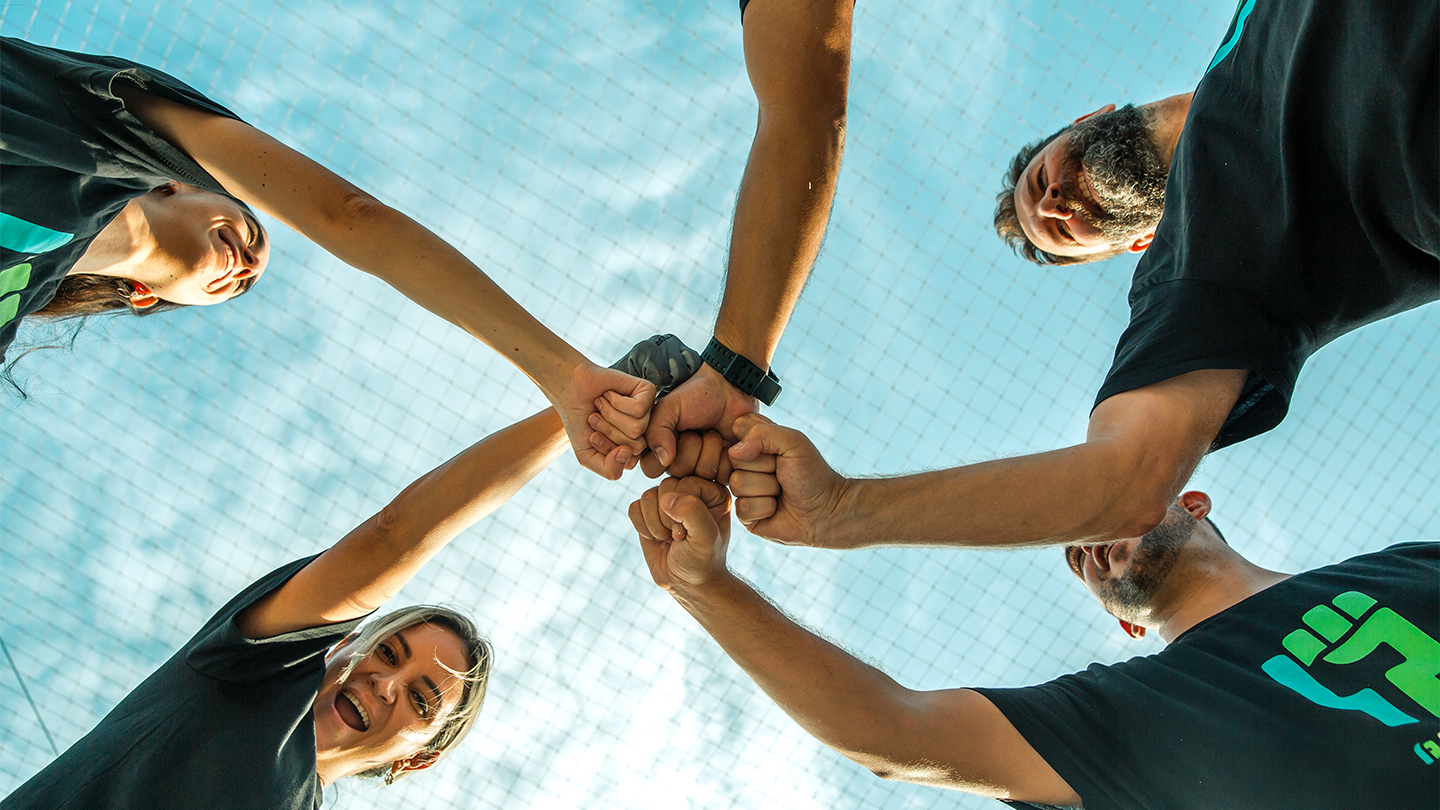 Team of volunteers from Grupo Ferrer joining their fists as a sign of teamwork and camaraderie.