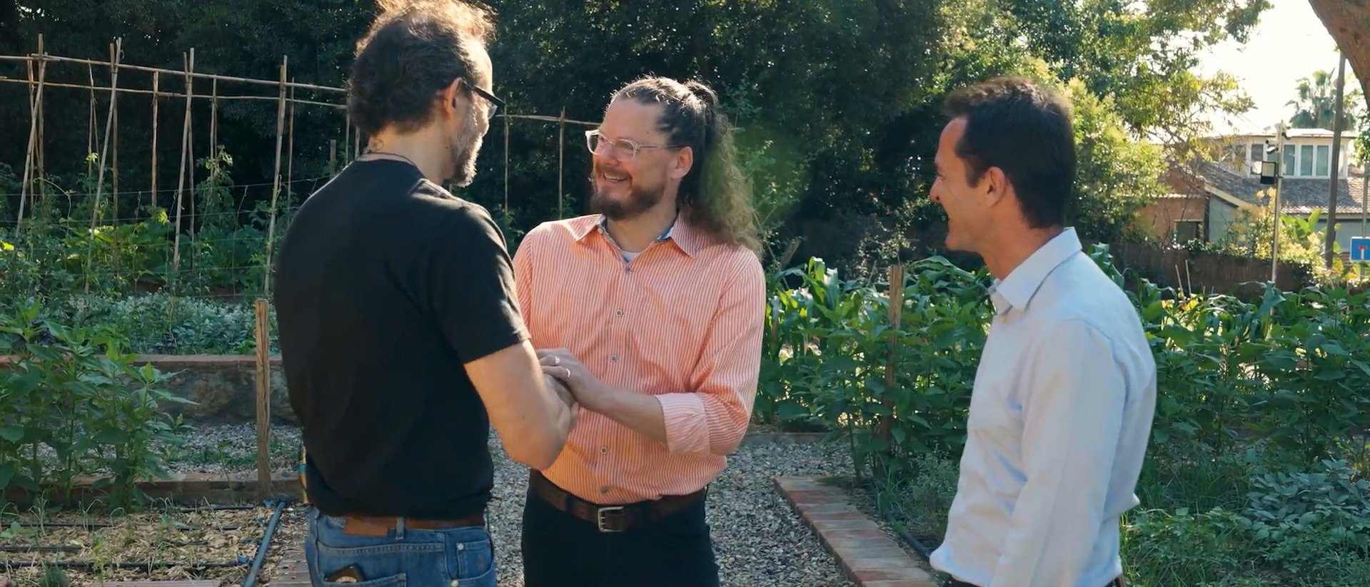 Three professionals talk in an orchard or outdoor garden during a Ferrer news story about purpose with Matthew McCarthy.